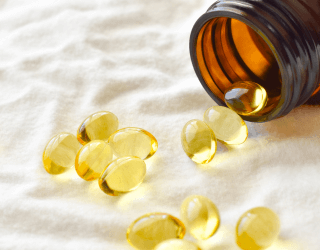 An Image of a spilled bottle of fish oil capsules on a white surface, highlighting the translucent golden omega-3 supplements.